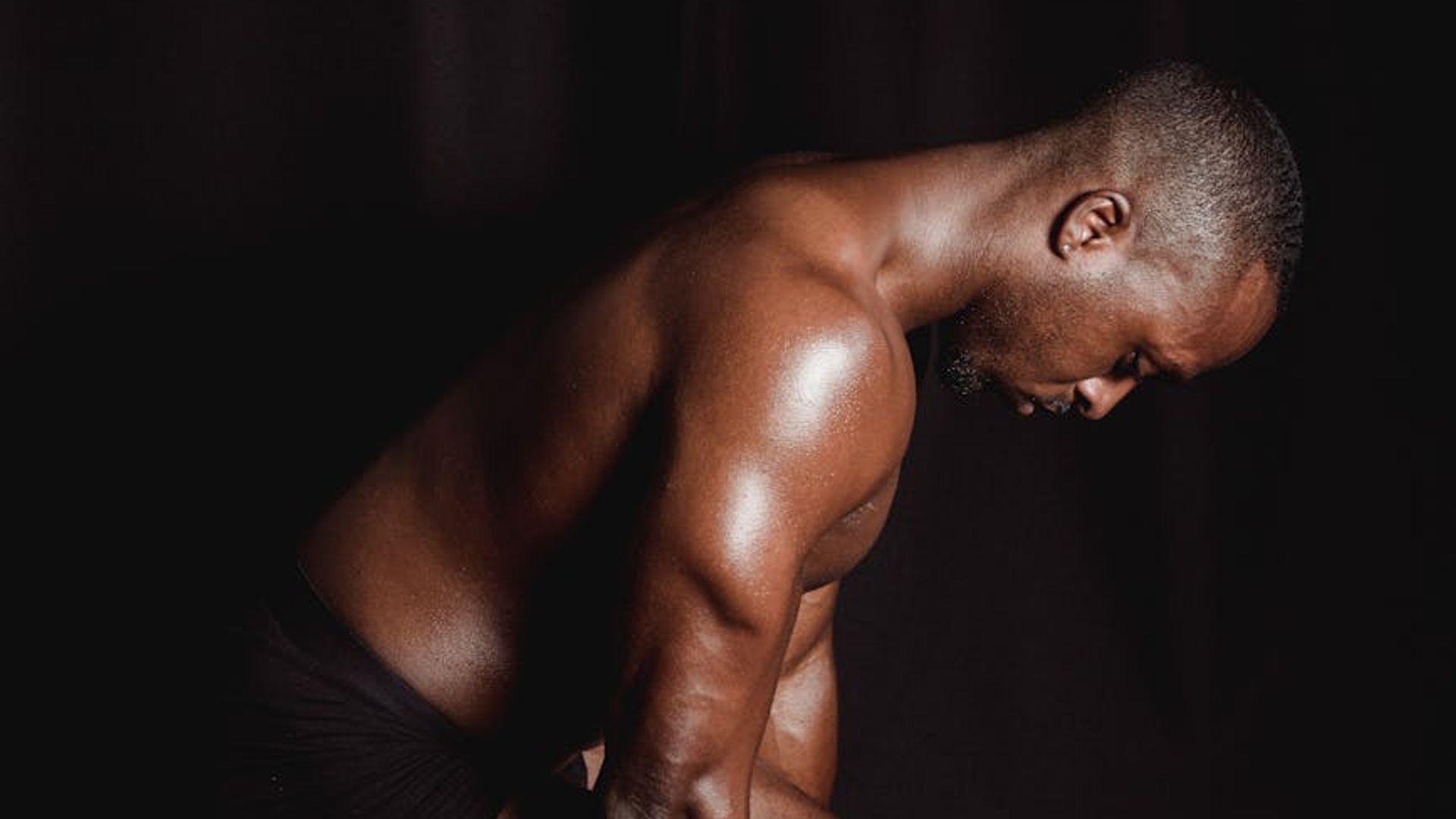 Man performing a controlled strength exercise in a minimalist dark room.